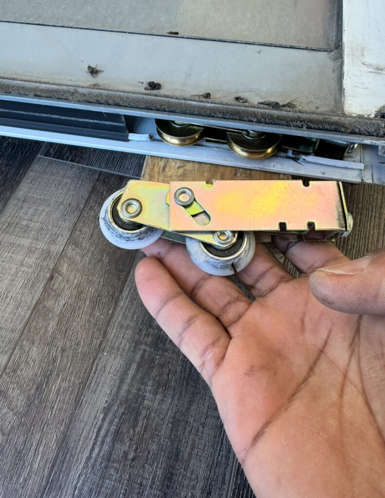 old worn out plastic patio door roller compared to newly installed metal roller.