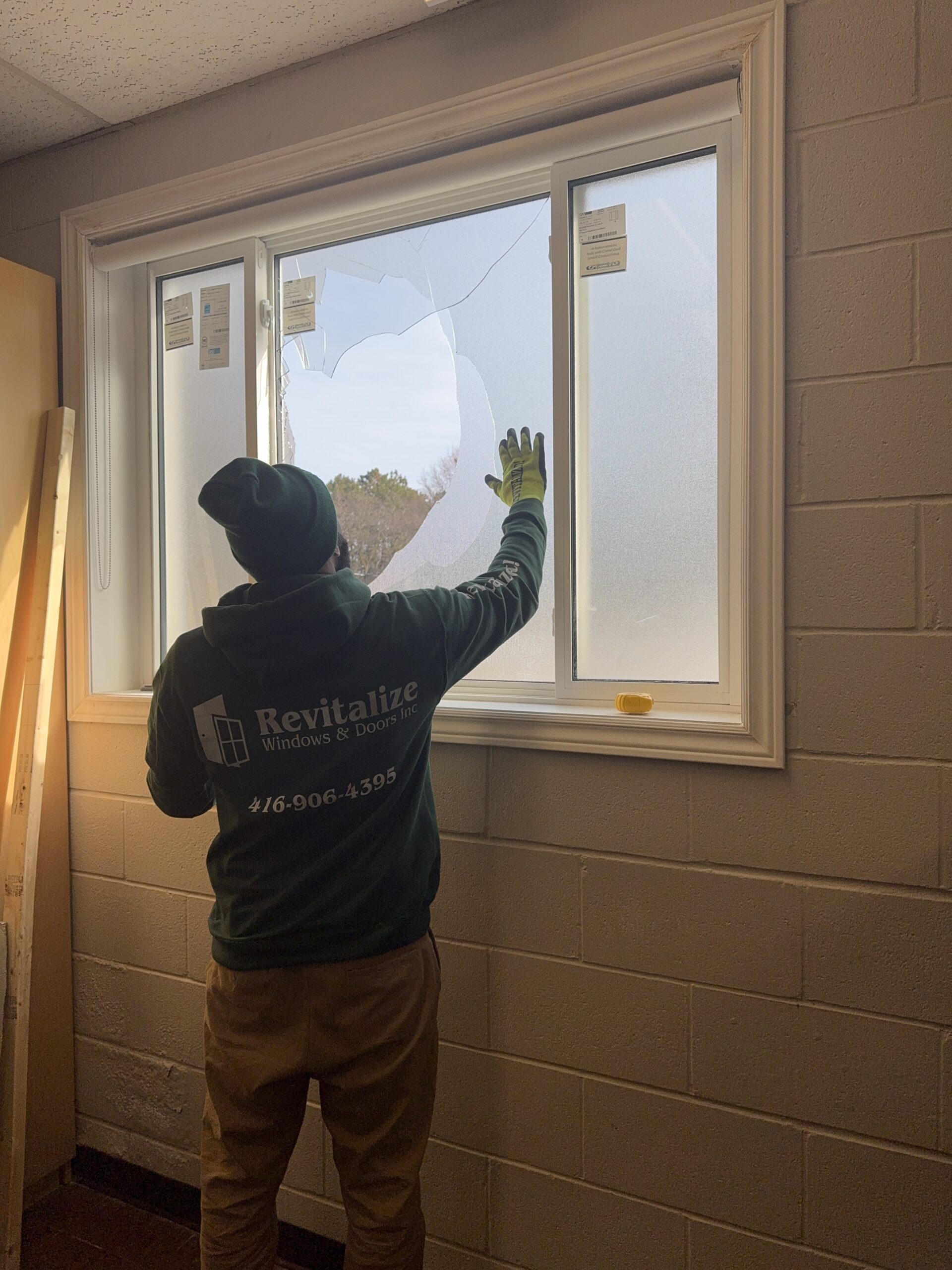 revitalize windows and doors technician inspecting broken window pane.