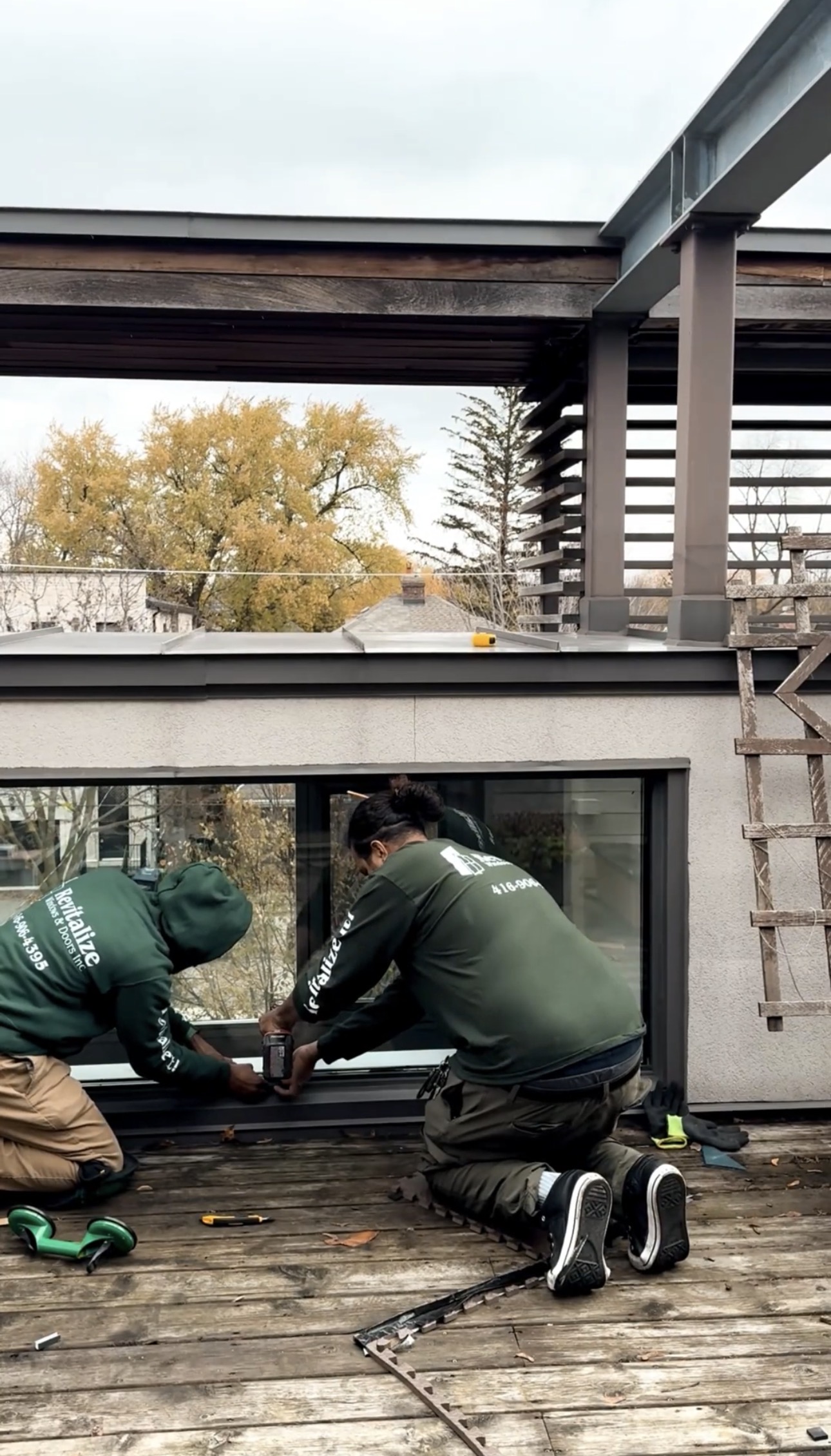 two window technicians from revitalize windows and doors securing new window glass pane in place.